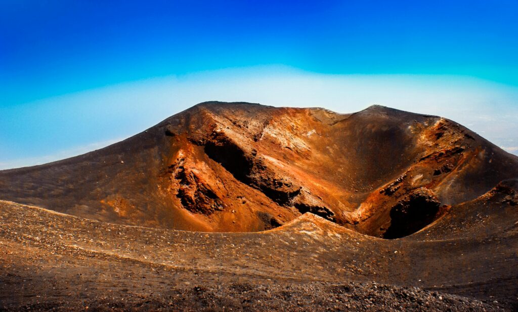 Explore the breathtaking volcanic crater landscape with vibrant colors under a clear blue sky in Sicily.